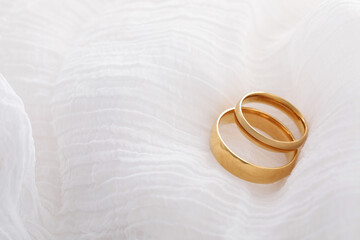 Beautiful golden wedding rings on white fabric, space for text