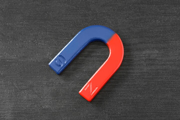 One horseshoe magnet on black wooden background, top view