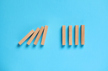 Domino effect. Wooden blocks on light blue background, flat lay