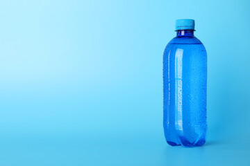 Plastic bottle of water on light blue background. Space for text