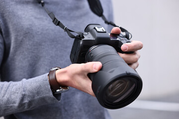 Professional photographer with modern camera outdoors, closeup