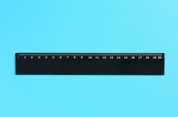 One black ruler on light blue background, top view