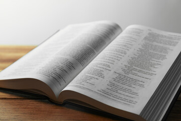 Obraz premium Open Holy Bible in English language on wooden table, closeup