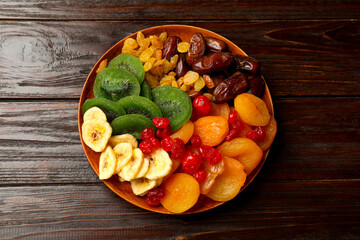 Mix of different dried fruits in bowl on wooden table, top view
