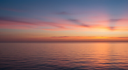 Obraz premium Gentle pink and orange hues reflecting off a calm evening sky over the ocean horizon