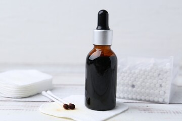 Bottle of iodine with dropper, cotton pads and swabs on white wooden table, closeup