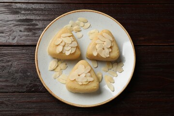 Pieces of delicious semolina halva with almond flakes on wooden table, top view