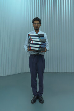 Businessman Standing with Stack of Office Binders