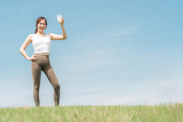 運動時にプロテイン・EAA・ドリンクを飲む女性(青空)
