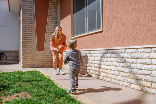 Mom playing ball with her son near the house