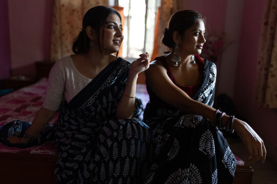 Two Indian woman sitting inside house making conversation