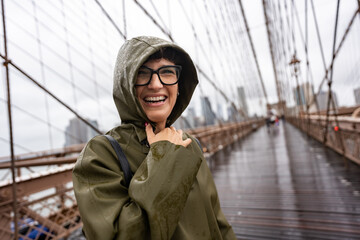 Happy tourist laughing under the rain on Brooklyn Bridge