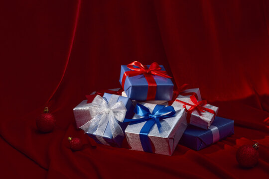 Festive holiday gifts with vibrant ribbons displayed on a red table