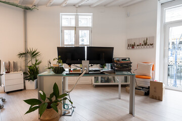 Coworking office desk with two monitors and plants promoting wellbeing