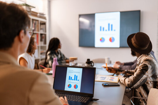 Business team analyzing charts and graphs on laptop and tv