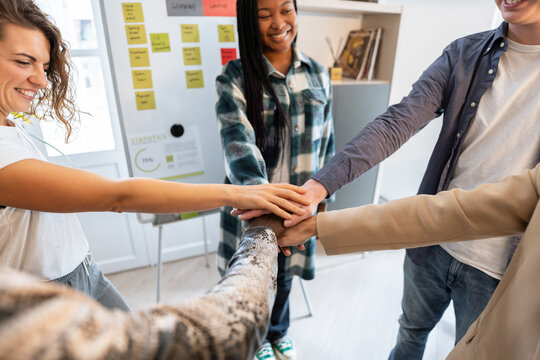 Startup team joining hands in coworking space: showing unity