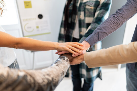 Coworkers joining hands in office teamwork collaboration