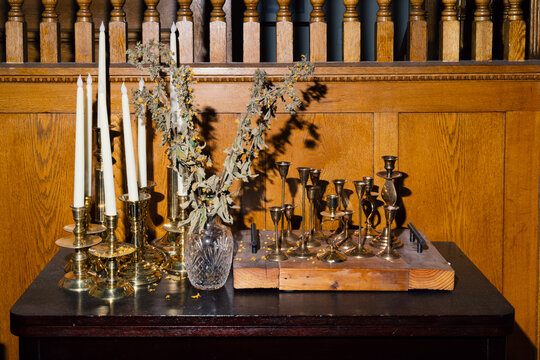 Collection of old candlesticks on table with dried up plant