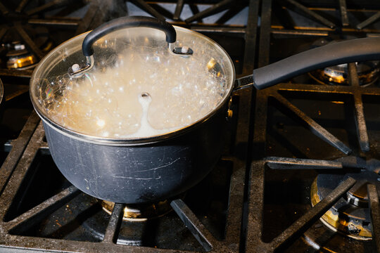 Simmering pot of rice on the stove with the lid on and steam rising