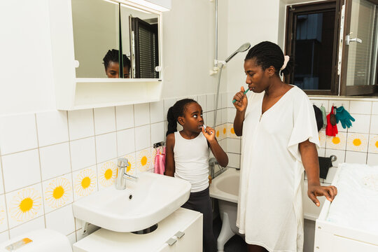 Mother and Daughter Brushing Teeth Together at Night