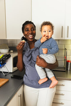 Mother and Baby Son Sharing Bread at Kitchen Counter