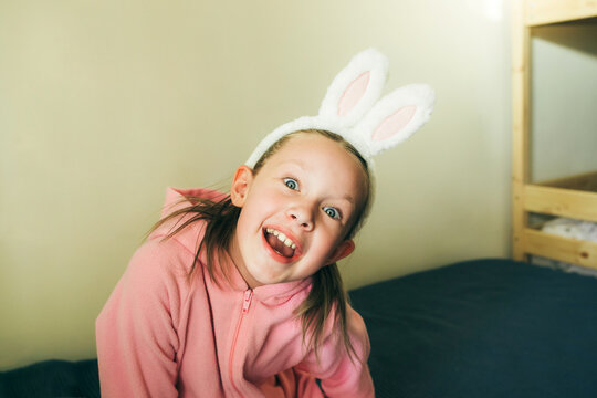 Portrait of laughing girl in Easter rabbit costume at home.