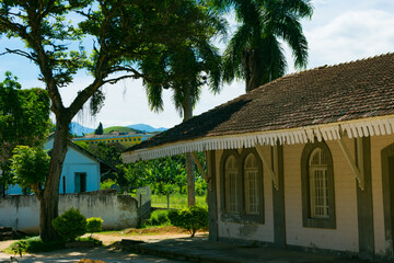 Side view of a historic train station with palm trees and distant buildings, Queluz, SP.