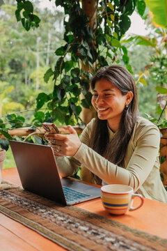 Happy woman texting in her phone while working in laptop