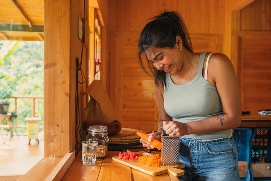 Happy woman grating vegetables