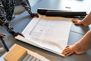 Architects examining blueprints in coworking office discussing