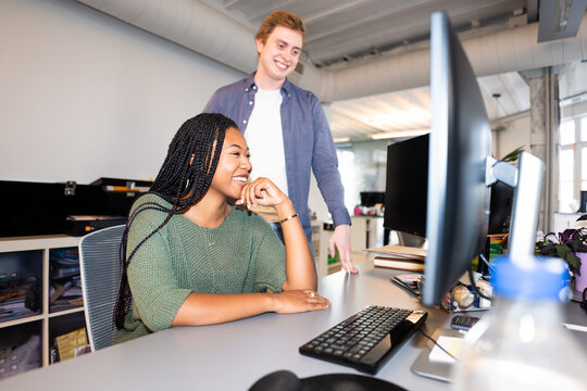 Coworkers discussing project, looking at computer screen