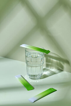 Glass of Water With Green Tea Packets in Stylish Setting