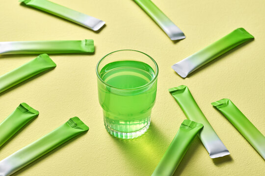 Refreshing Green Drink with Single-Serve Sachets on Yellow Background