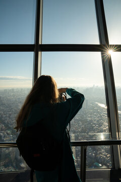 Woman photograph city view through the window