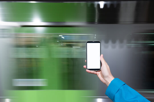 Woman hand holding phone in front of subway in motion