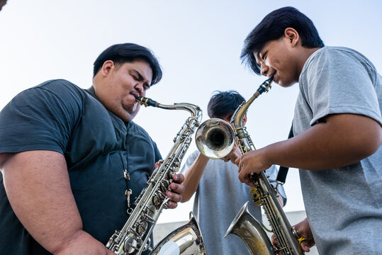 Three Musicians Playing Saxophones and Trumpet Outdoors