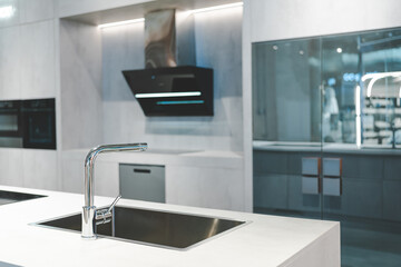 a sleek and modern kitchen sink and faucet set against a backdrop of dark cabinetry and a marble countertop. The faucet is a single-handle design with a tall.