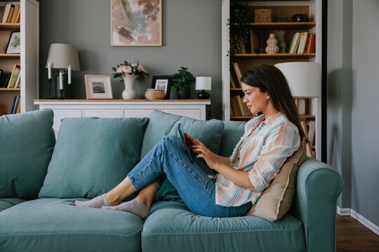 Woman Relaxing at Home Using Tablet On Comfortable Sofa