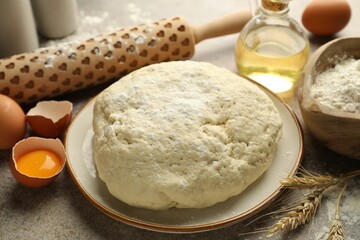 Fresh dough, ingredients and rolling pin on grey table, closeup