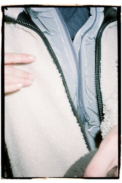 Hands opening zipper detail of winter jacket and layers of clothes 