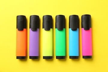 Bright highlighters on yellow background, flat lay