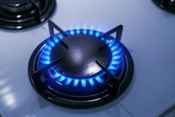 Gas burner with blue flame on stove, closeup