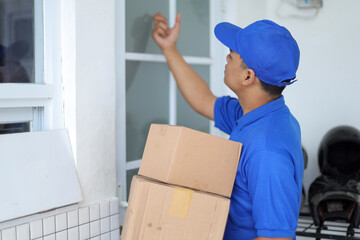 Side View of Deliveryman in Blue Uniform Knocking on Customer's Door