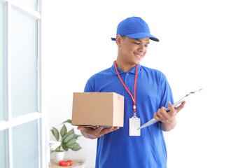 Delivery Man in Blue Uniform Work as Dealer Courier Hold Cardboard Box While Looking at Clipboard