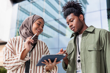 Confident diverse professionals discussing over digital tablet