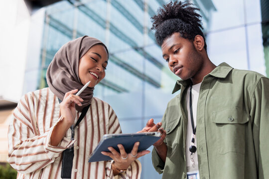Confident diverse professionals discussing over digital tablet