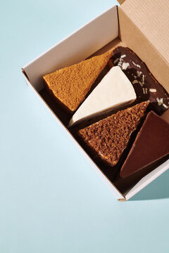 Assorted pieces of cake in a box on a light blue background