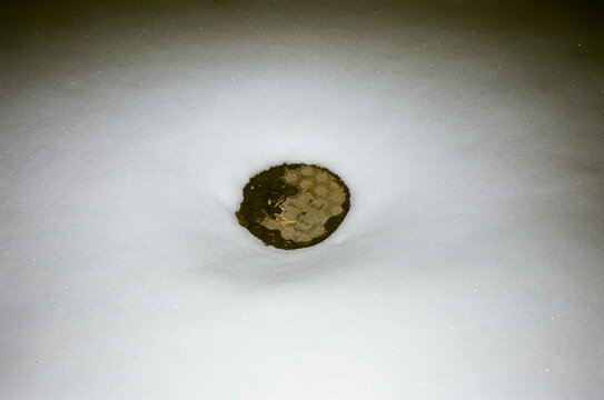 Hot manhole appearing in the middle  of snow cover street 