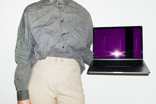 Person holding a laptop with broken screen in office workplace