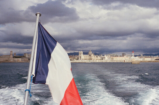 French Flag on Boat with Marseille Cityscape Background